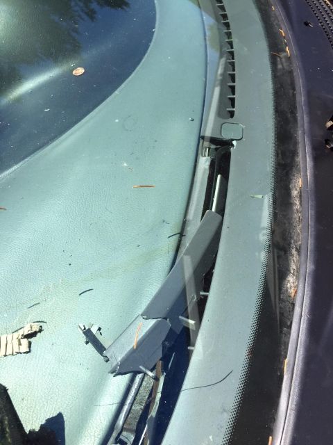 1995 Ford Probe - A close-up view of a broken windshield wiper arm on a car. The plastic arm is cracked and detached from its base, revealing metal component…