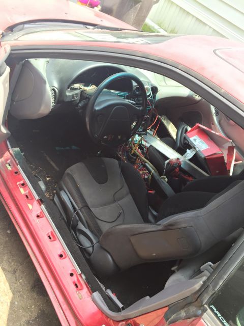 1995 Ford Probe - The interior of a red 1995 Ford Probe is shown with the driver's door open. The dashboard and steering wheel are visible, along with expose…