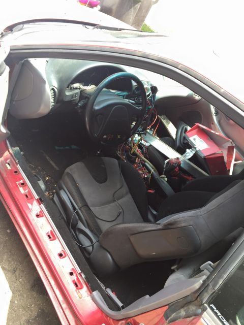 1995 Ford Probe - Interior view of a red 1995 Ford Probe with the driver's door open, showing the dashboard, steering wheel, and front seats. The interior ap…