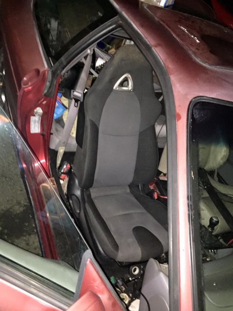 1995 Ford Probe - Interior view of a red car with a racing seat installed. The driver's side door is open, revealing the seat and surrounding interior compon…