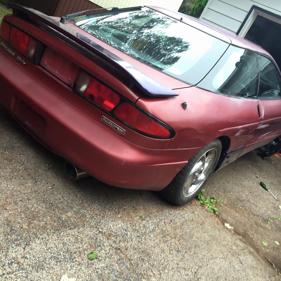 Red 1995 Ford Probe, rear passenger side view, parked on a concrete driveway.