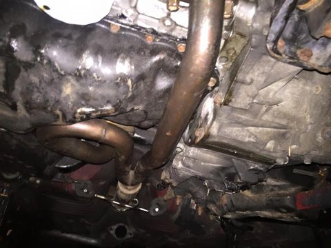 1995 Ford Probe - Underside view of a vehicle's engine bay and exhaust system, showing a black oil pan and a section of the exhaust manifold. The transmissio…