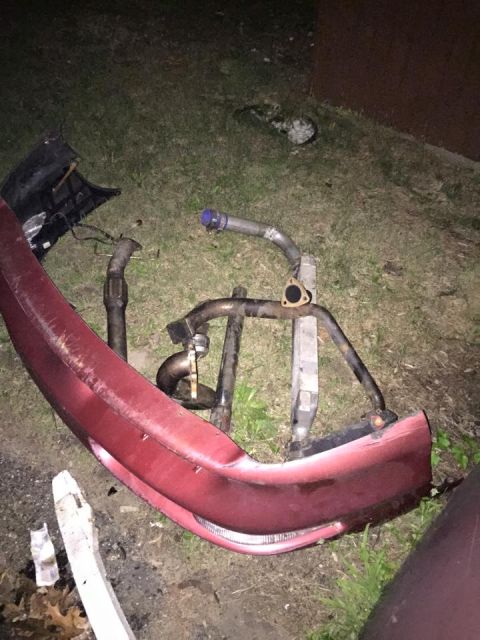1995 Ford Probe - A red car bumper is lying on the ground with various exhaust pipes and intercooler components arranged on top of it. The scene appears to b…