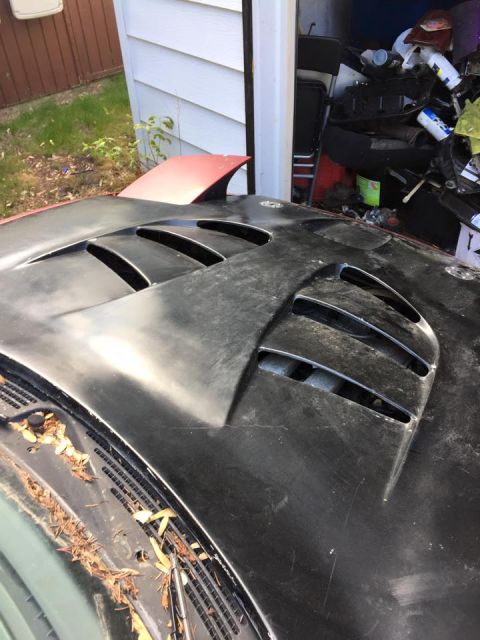 1995 Ford Probe - A close-up view of a black car hood with multiple vents. A red spoiler is visible on the upper left side of the hood.