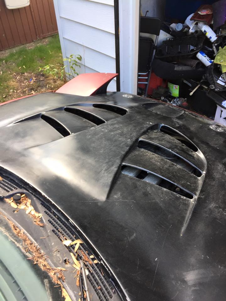Black car hood with vents and a red spoiler.