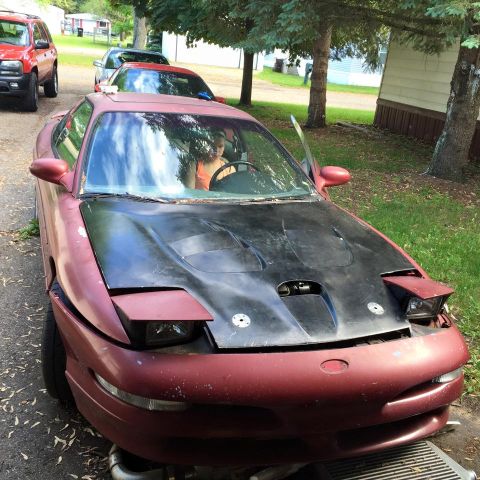 1995 Ford Probe - A maroon Ford Probe with a black hood sits in a driveway with a person visible in the driver's seat. The car appears to be undergoing some…