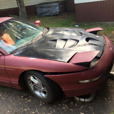 1995 Ford Probe - A maroon 1995 Ford Probe is parked outdoors with a black aftermarket hood featuring multiple vents. The front of the car is visible, showin…