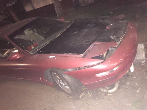 1995 Ford Probe - The front end of a red coupe is damaged, with the hood open and a headlight missing.