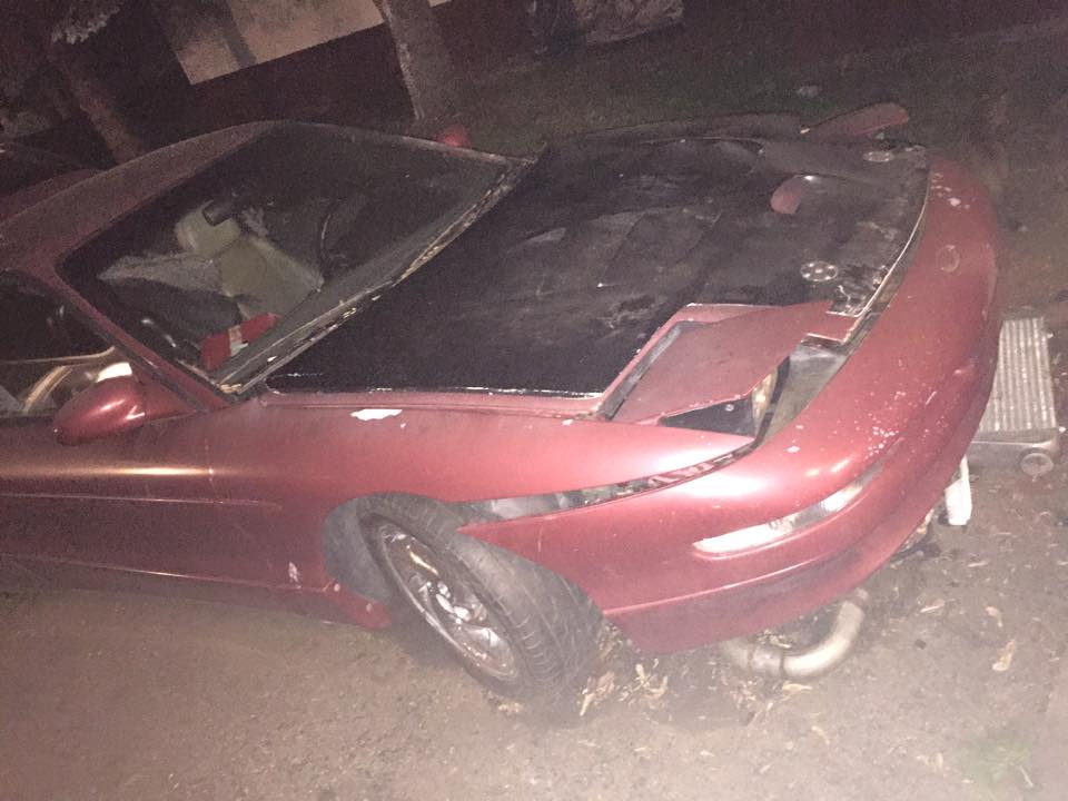 red coupe, hood open, front end damaged, headlight missing on passenger side
