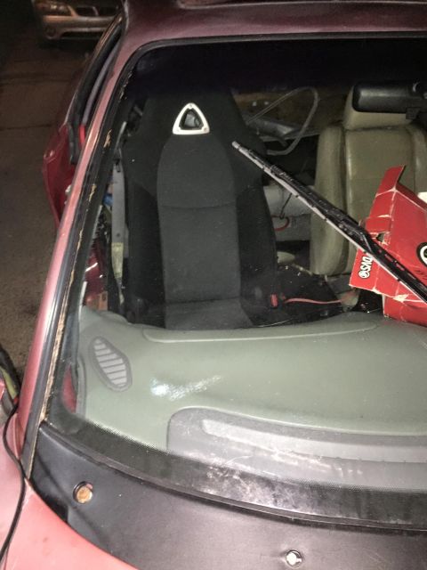 1995 Ford Probe - Interior view of a damaged red car, showing a racing seat and a cardboard box on the dashboard.