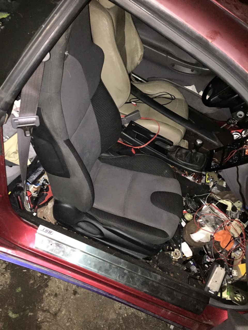 Interior view of a car with racing seats, roll cage, and messy wiring