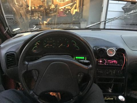1995 Ford Probe - Interior view of a car's dashboard, showing the steering wheel, instrument cluster, and center console with a radio and an additional gauge.