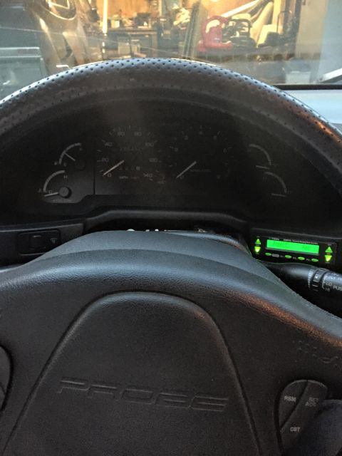 1995 Ford Probe - The interior of a car is visible, the word 'PROBE' embossed on the steering wheel and a glowing green digital display unit.