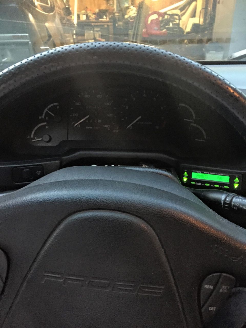Interior view of a car with 'PROBE' on the steering wheel and a green digital display