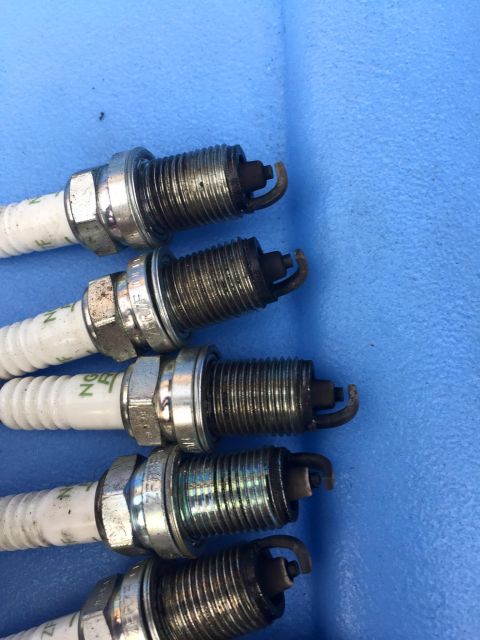 1995 Ford Probe - Set of four used spark plugs, some showing wear on the electrodes.