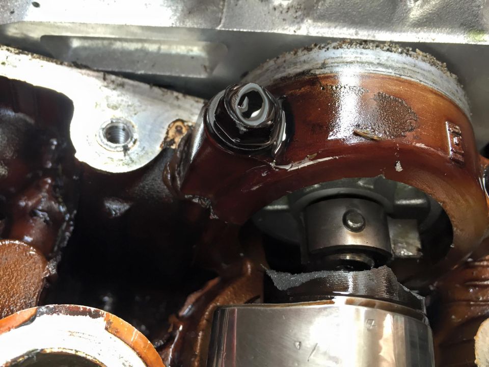 Close-up of engine components with oil residue and a bolt