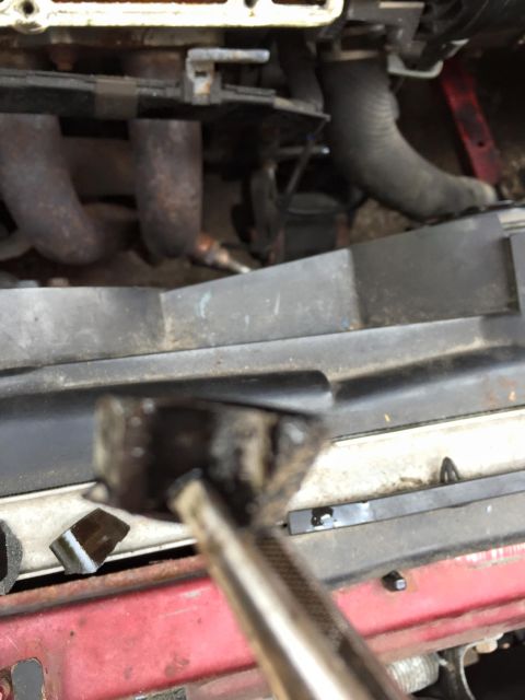 1995 Ford Probe - Close-up view of engine bay components, including exhaust manifold and hoses, with a tool in the foreground.