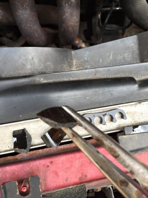 1995 Ford Probe - A close-up shows a black engine part being held by pliers, with a spark plug wire holder visible in the background.
