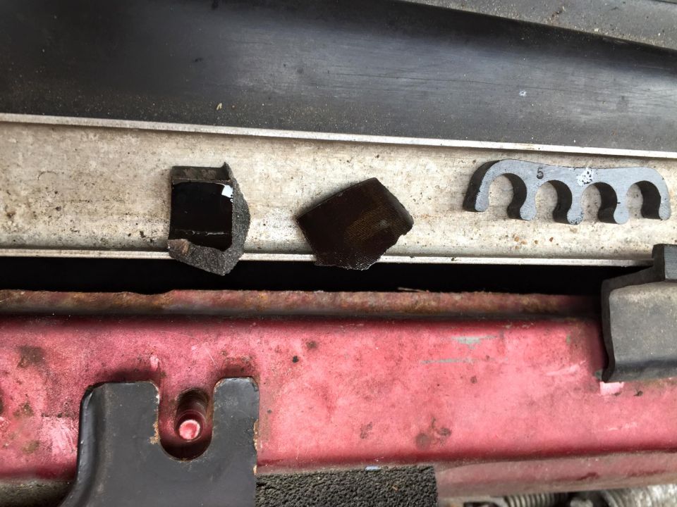 Three broken black plastic pieces and a black wire loom clip with the number 5 visible