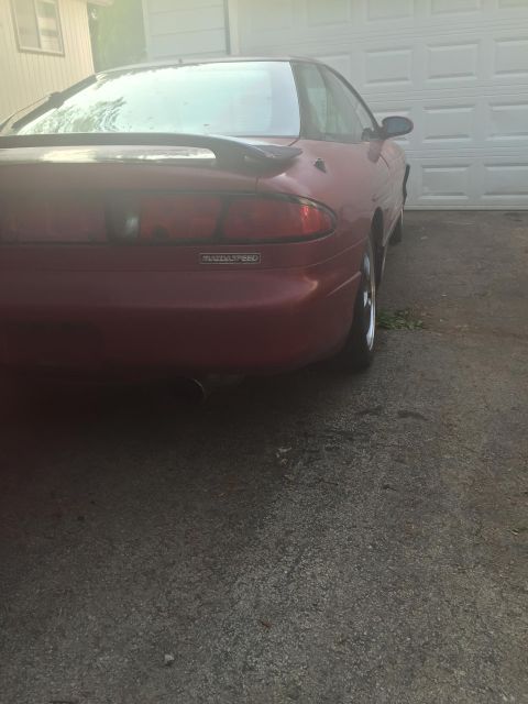 1995 Ford Probe - Rear view of a red 1995 Ford Probe coupe parked in front of a garage door.