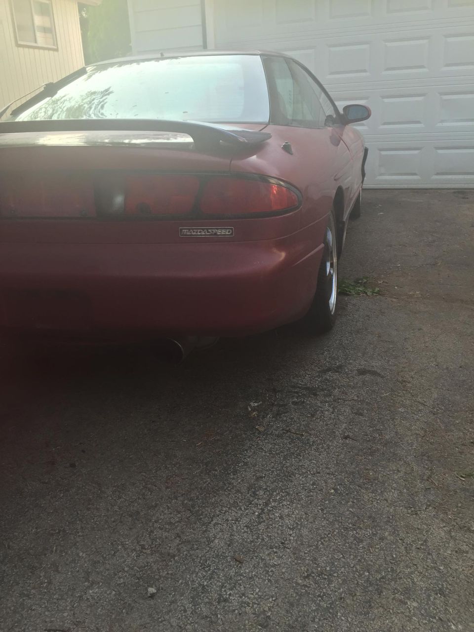 Red 1995 Ford Probe coupe, rear view, parked in driveway. Spoiler on trunk