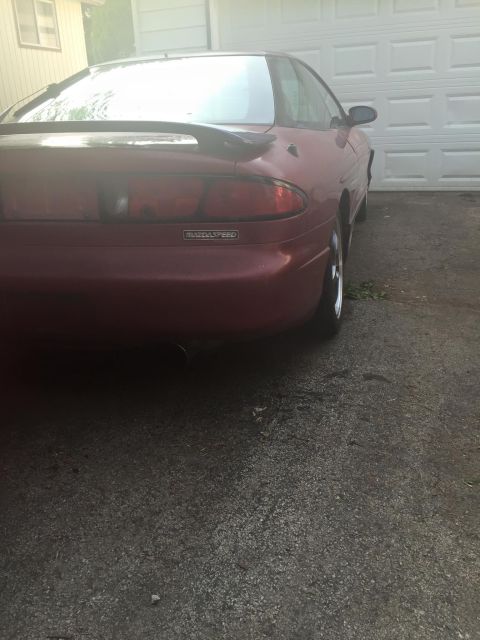 1995 Ford Probe - Rear view of a red MazdaSpeed coupe parked in front of a garage door.