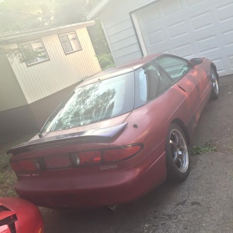 1995 Ford Probe - A red 1995 Ford Probe is seen from the rear in a driveway next to a garage and a small building.