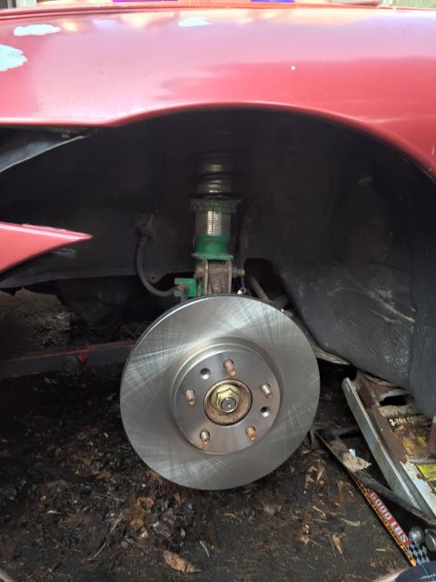 1995 Ford Probe - Front brake rotor and suspension assembly of a red car.