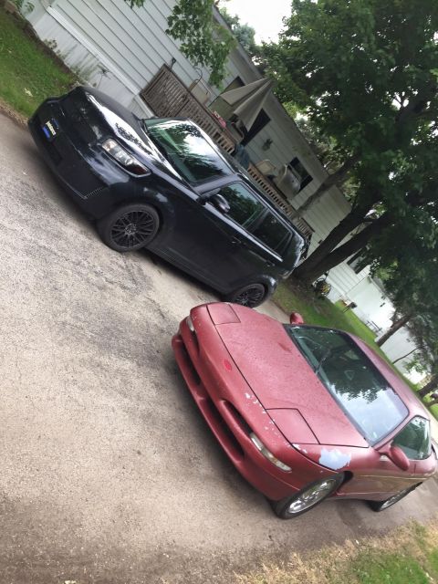 1995 Ford Probe - A red 1995 Ford Probe is parked next to a black SUV.