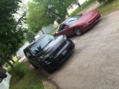 1995 Ford Probe - Two vehicles, a red sports car and a black SUV, are parked on a driveway.