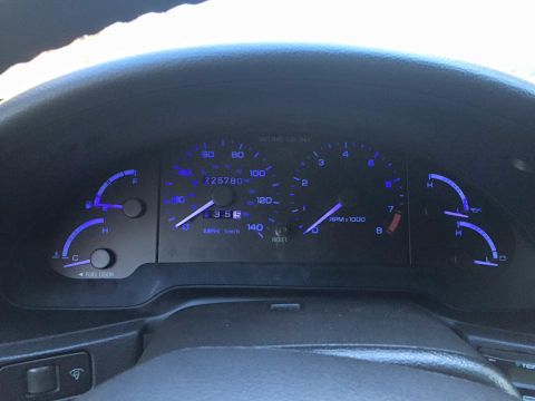 1995 Ford Probe - The vehicle's interior shows the dashboard with illuminated gauges and a high mileage reading on the odometer.