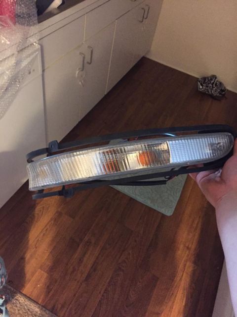 1995 Ford Probe - A clear car headlight assembly with an amber turn signal is held for inspection.