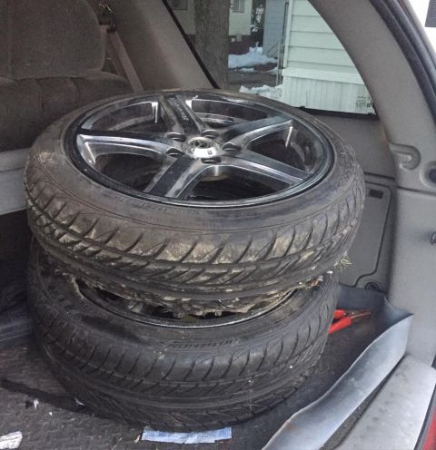 1995 Ford Probe - Two tires and rims are stored in the back of a vehicle.