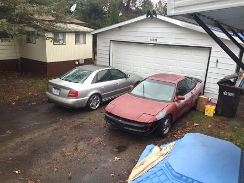 1995 Ford Probe - A red coupe with pop-up headlights and front-end damage is parked in a driveway.