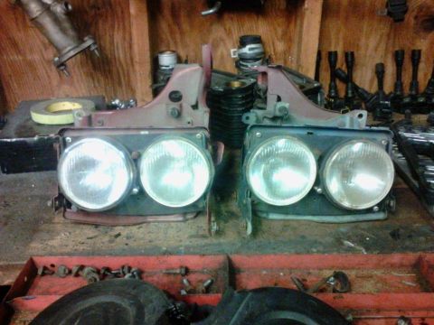 1995 Ford Probe - A pair of car headlights are displayed on a workbench with various tools and parts in the background.