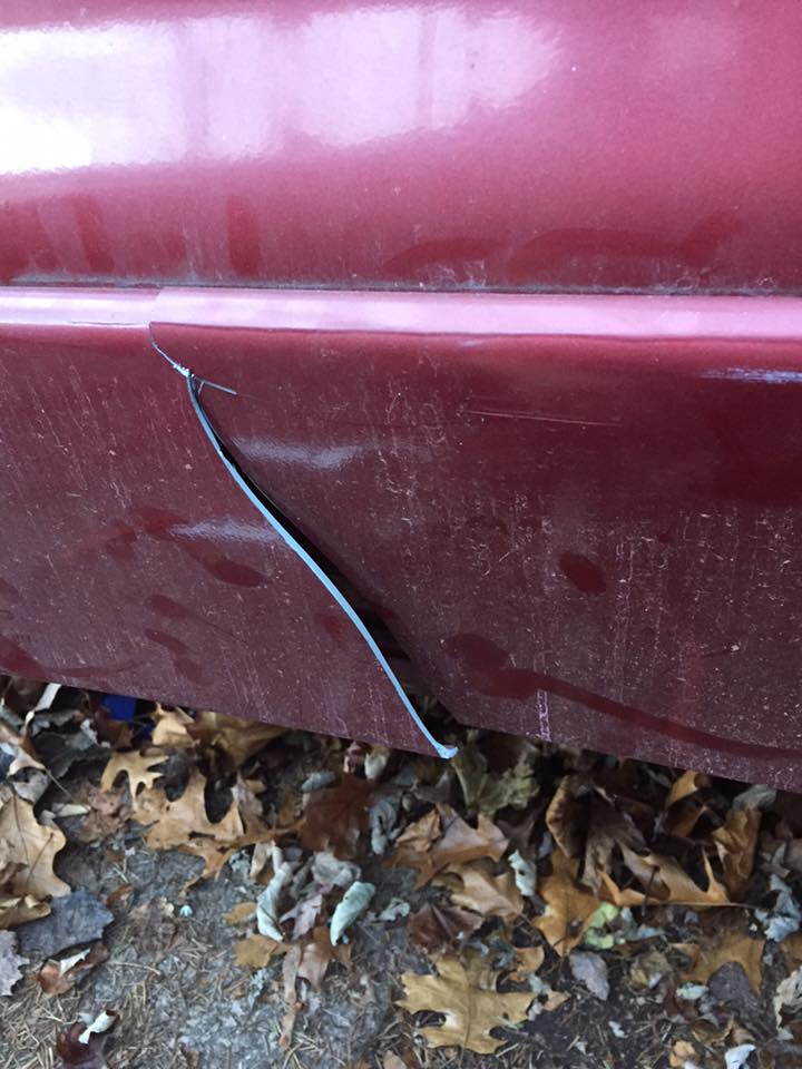 Close-up of a detached piece of black trim on a red car's lower body panel