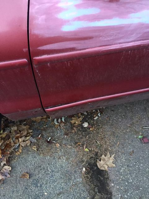 1995 Ford Probe - Close-up of a red car's side panel and door, with debris on the ground.