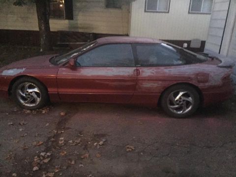 1995 Ford Probe - This red coupe appears to be a 1995 Ford Probe, showing signs of bodywork with primer visible.