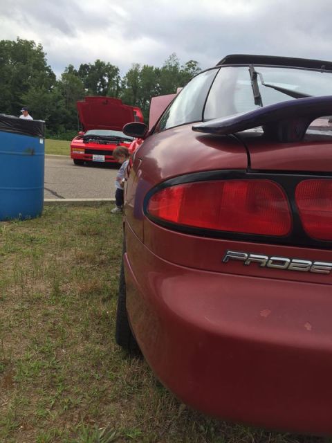 1995 Ford Probe - Rear view of a red car with a spoiler and 'PROBE' badging, with another red car in the background.