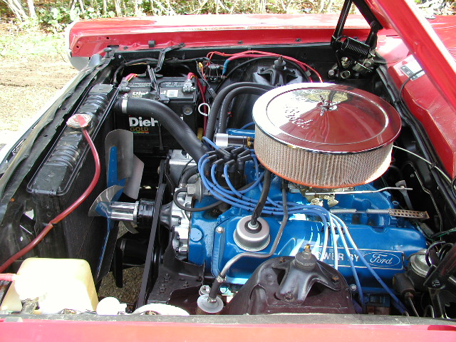 Engine bay of red Ford Ranchero with blue Ford V8, chrome air cleaner, and DieHard battery