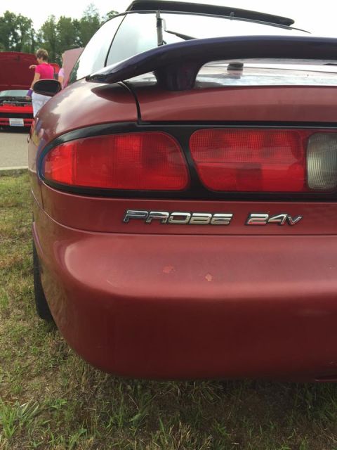1995 Ford Probe - Rear view of a red car with a spoiler and 'PROBE 24V' badging, with another vehicle in the background.