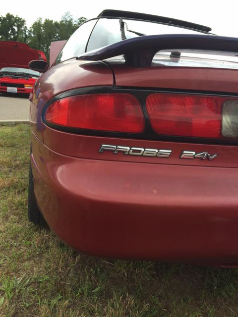 1995 Ford Probe - The rear of a red Ford Probe is shown, with a second red vehicle visible in the background.