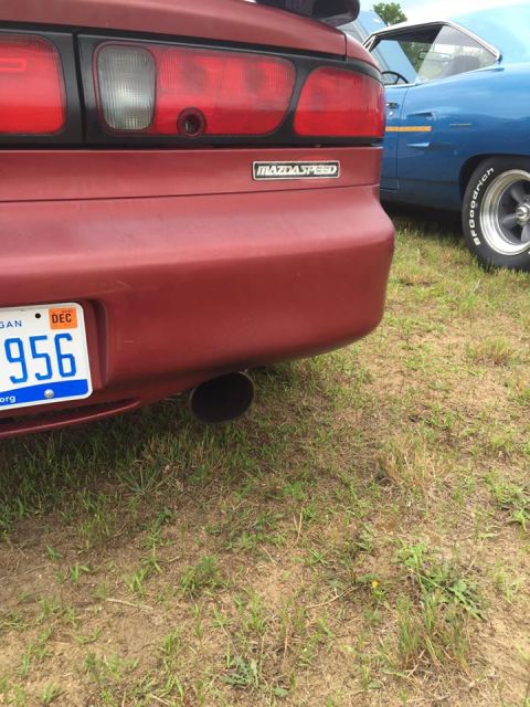 1995 Ford Probe - Rear view of a red car a Mazdaspeed badge and an exhaust pipe, with a blue car visible in the background.