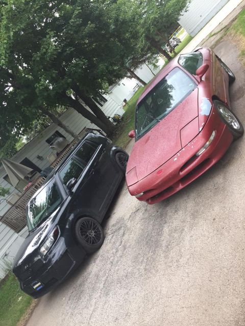 1995 Ford Probe - Two vehicles parked on a driveway, a red sports car and a black SUV.
