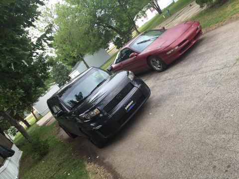 1995 Ford Probe - A red 1995 Ford Probe is parked behind a black Scion xB on a paved driveway.