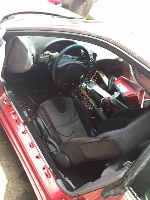 1995 Ford Probe - The interior of a red car shows a disassembled dashboard with exposed wiring and dark seats.