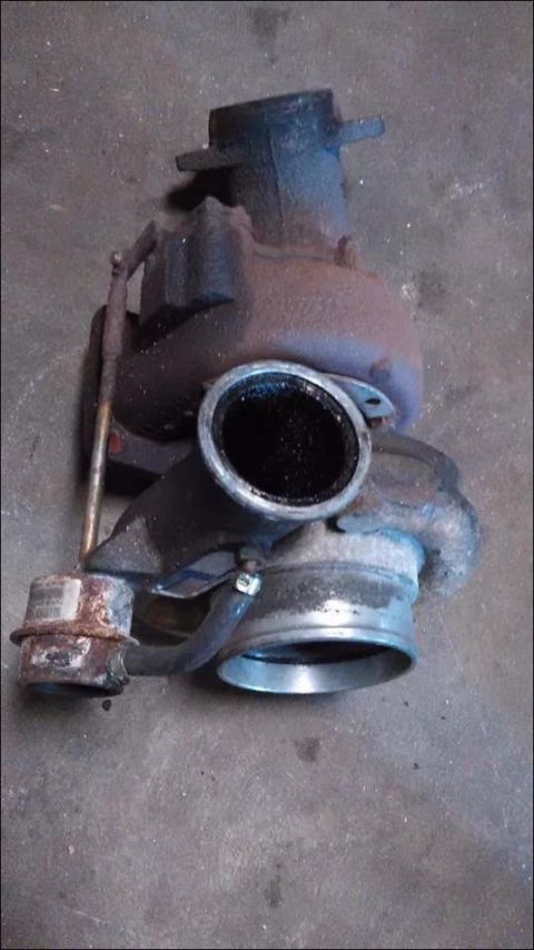 1995 Ford Probe - A used turbocharger, showing signs of wear and soot buildup, rests on a concrete floor.