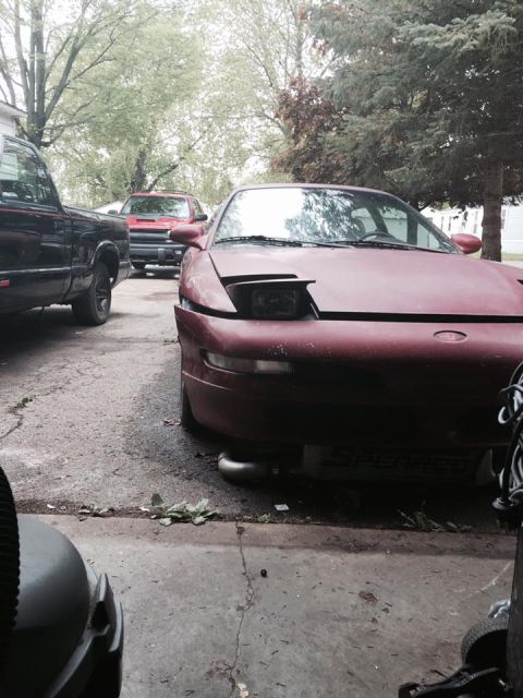 1995 Ford Probe - A red 1995 Ford Probe is parked in a driveway with other vehicles visible.