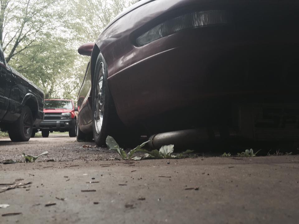 Rear view of a red Ford Probe with exhaust pipe visible, parked outdoors.