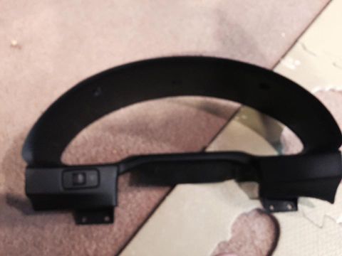 1995 Ford Probe - A black dashboard part, likely a gauge cluster surround, is shown from a slightly elevated angle against a textured, light brown surface.